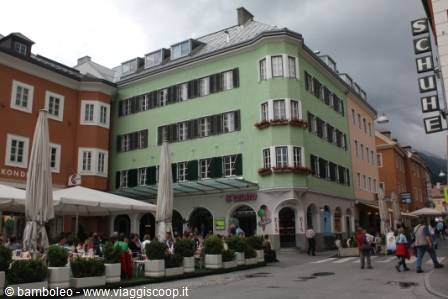 Green building with outdoor café in Innsbruck old town, cloudy sky