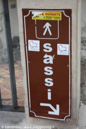 Brown sign with arrow pointing visitors toward the Sassi guided tour