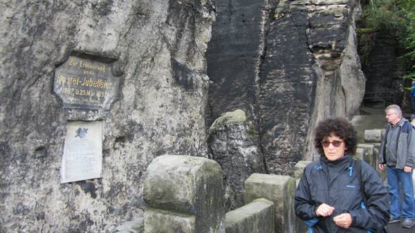 Woman in front of a commemorative plaque carved into sandstone rock
