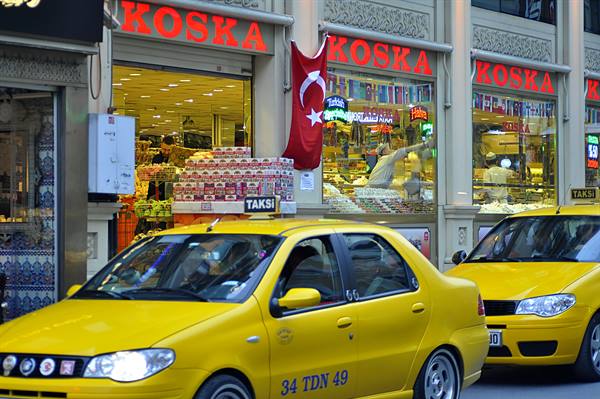 Yellow taxis outside Koska sweets shop with Turkish flag, Istanbul
