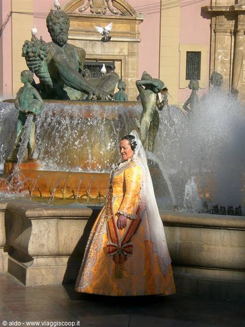 Woman in traditional fallera dress in front of Valencia's Turia fountain