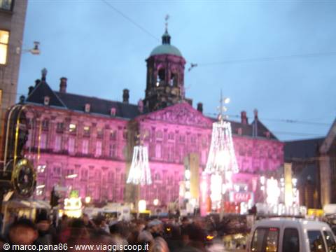 Amsterdam Royal Palace lit in pink with Christmas lights and crowds on Dam Square