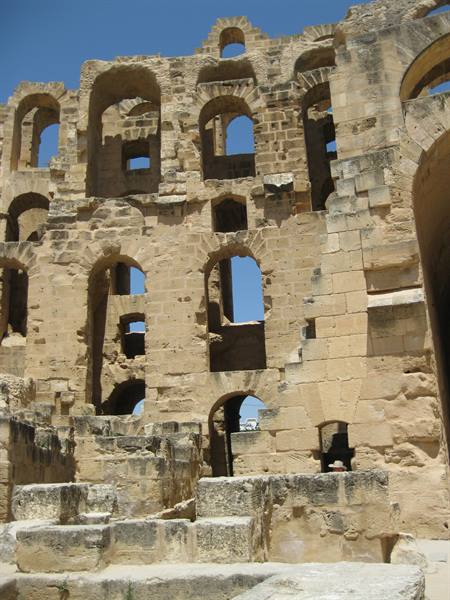 El Jem amphitheater: golden stone arches under bright blue sky