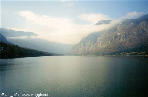still lake surrounded by rocky mountains wrapped in low clouds