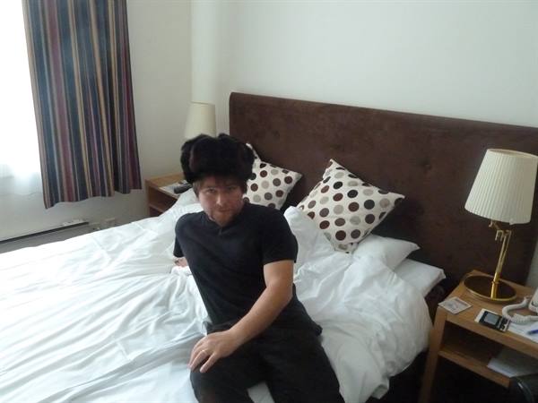 Boy sitting on a hotel bed in Oslo, daylight from the window