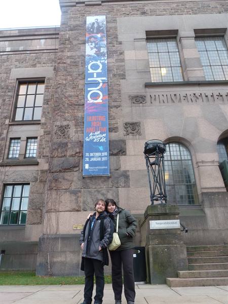 Couple in front of Oslo's National Gallery with an a-ha banner on grey stone