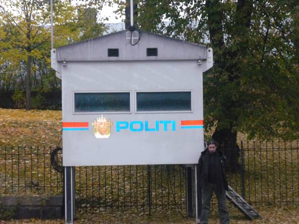 Man beside a raised Norwegian police booth on stilts, autumn in Oslo