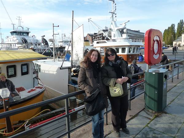 Two tourists at Aker Brygge harbor in Oslo, boats moored behind