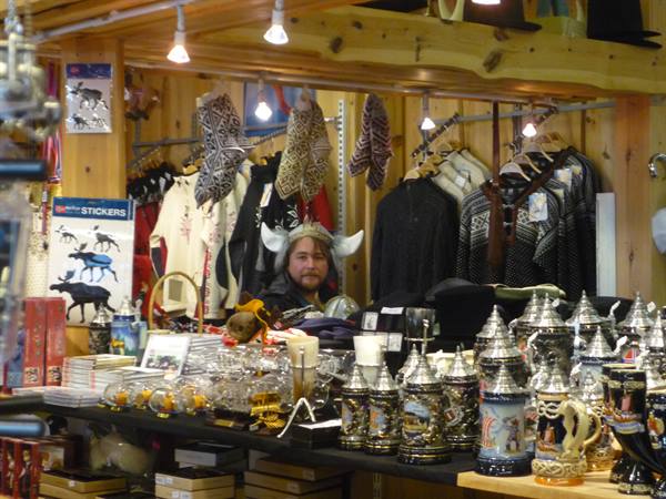 Vendor wearing a Viking helmet inside a wooden souvenir shop in Oslo