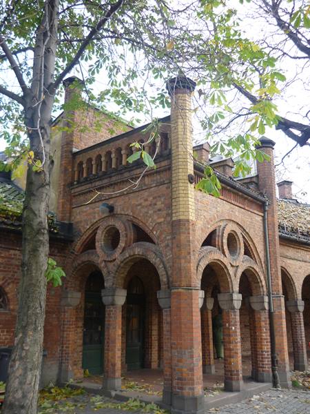 Red brick facade with arches and columns in Oslo, among autumn trees