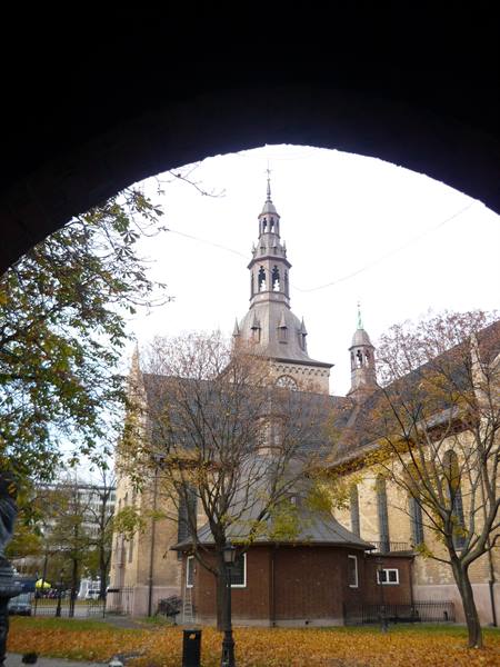 Oslo Cathedral seen through a stone arch, autumn trees around