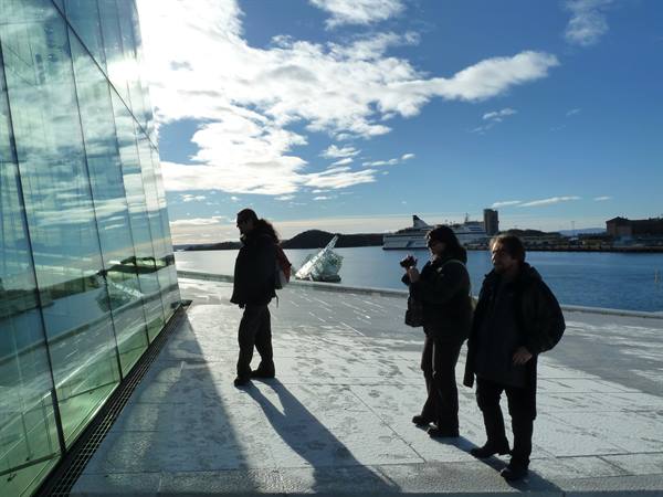 Tourists on the marble terrace of Oslo Opera House, glass and fjord