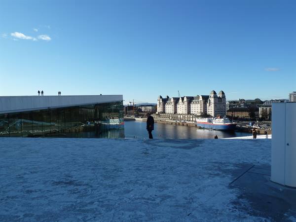 Visitors on the snowy roof of the Oslo Opera House, harbor and Libra building