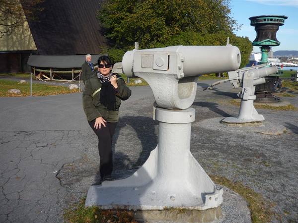 Tourist beside a grey naval cannon at the Fram Museum, Bygdøy, Oslo