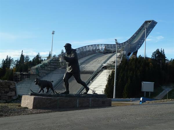 Bronze statue of a skier with dog in front of Holmenkollen ski jump, Oslo