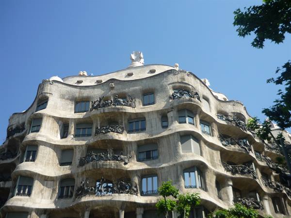 Facciata ondulata in pietra della Casa Milà sotto il cielo azzurro