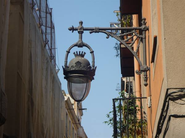 Lanterna in ghisa tra palazzi antichi, cielo azzurro, Barcellona