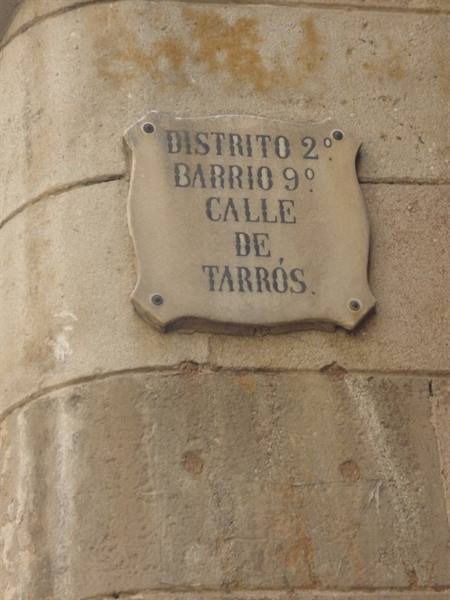 Stone street plaque on a wall reading Calle de Tarrós, district 2
