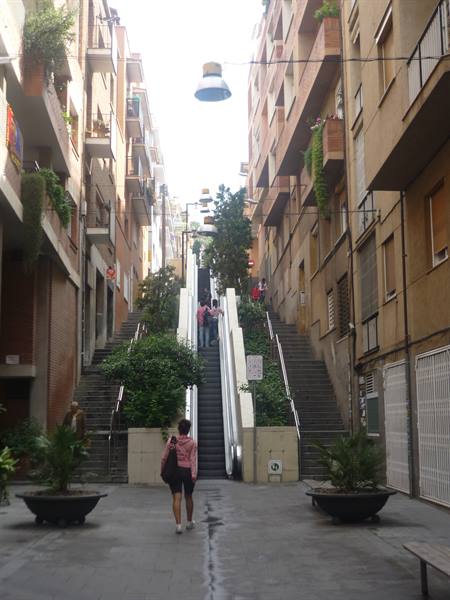 Girl with pink backpack walks toward outdoor escalators between residential buildings