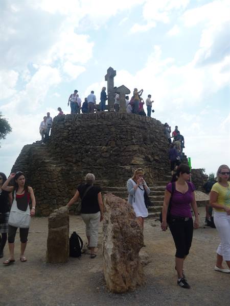 Tourists on the stone Calvary mound with cross at Park Güell, Barcelona