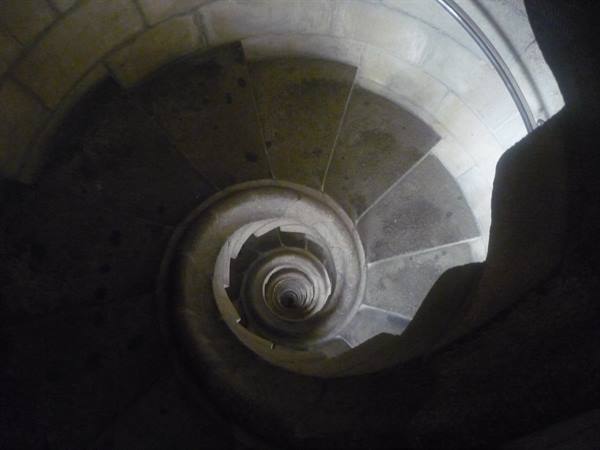 Stone spiral staircase seen from above, natural light on the step