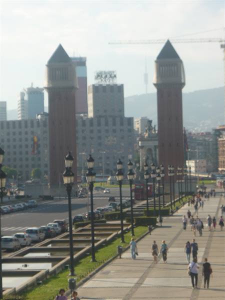 The Venetian Towers at Plaça d'Espanya, Barcelona, with pedestrians and lampposts along the avenue