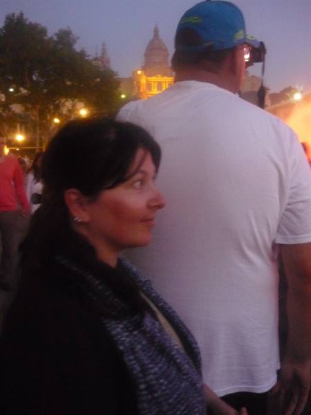 Woman in the evening crowd, man in blue cap beside her, square lights glowing