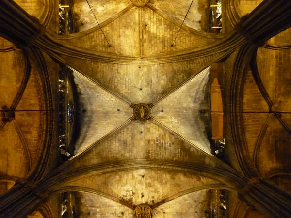 Stone ribbed vaults of the cathedral, lit by golden light