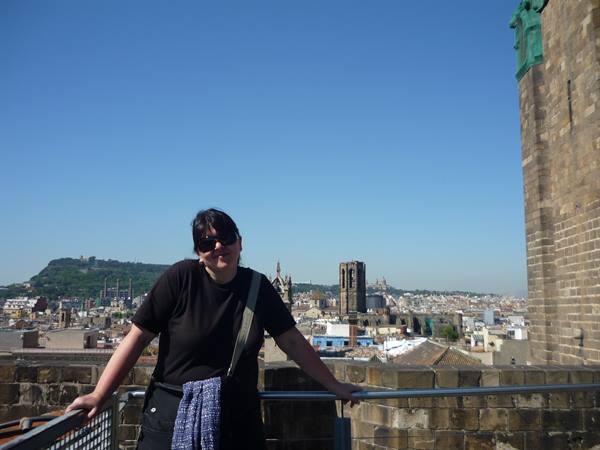 Woman in sunglasses on a stone terrace, Barcelona rooftops and bell tower behind