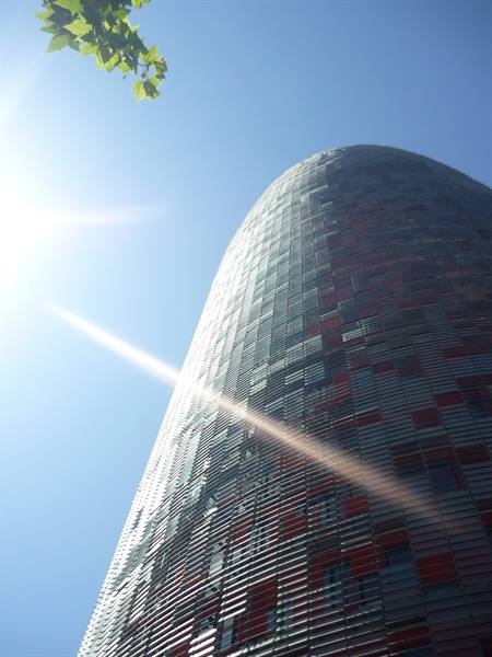 Agbar Tower in Barcelona, red and blue glass facade under sunlight
