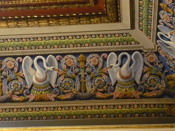 Painted ceiling with white swans among colorful arabesques on a gilded frame