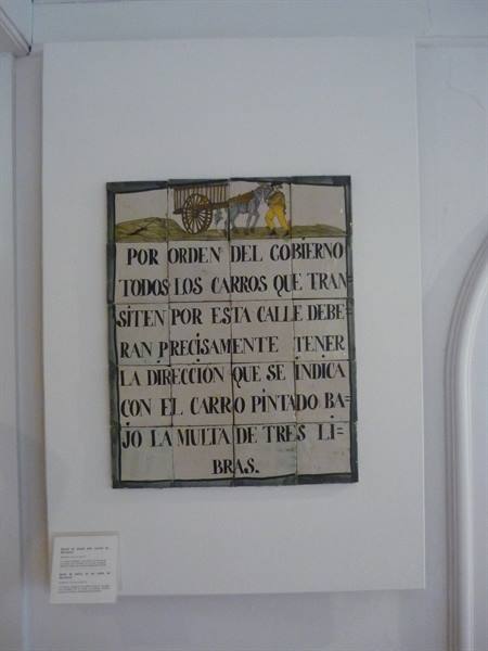 Historic tiled sign with painted inscription about cart rules, mounted on white wall