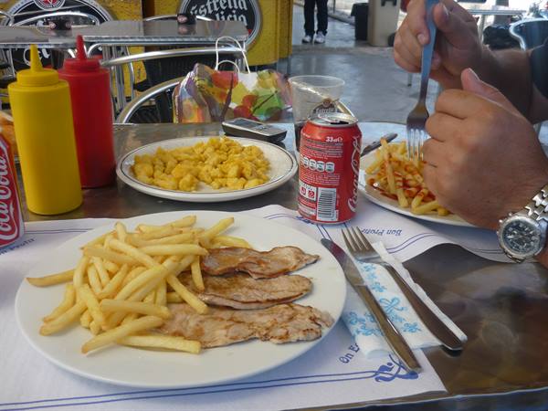 Plates with fries, meat and eggs on a bar table