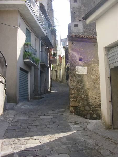 Steep cobbled alley between old houses with flowered balconies
