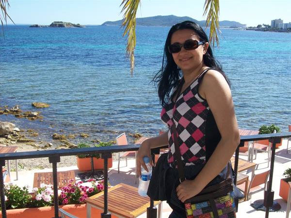 Smiling woman in sunglasses on a seaside terrace with palm and flowers