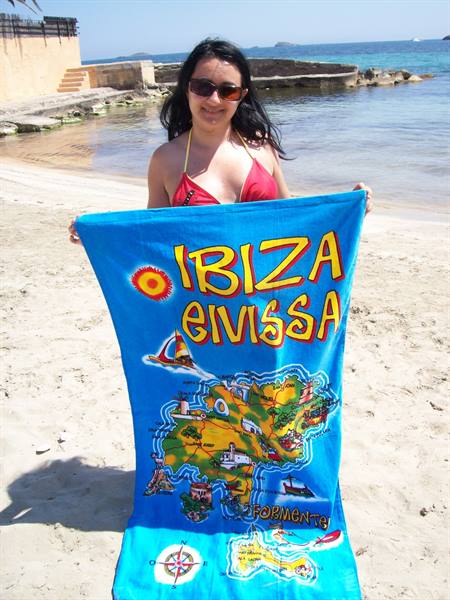 Woman in red bikini holds a blue Ibiza map towel on the beach
