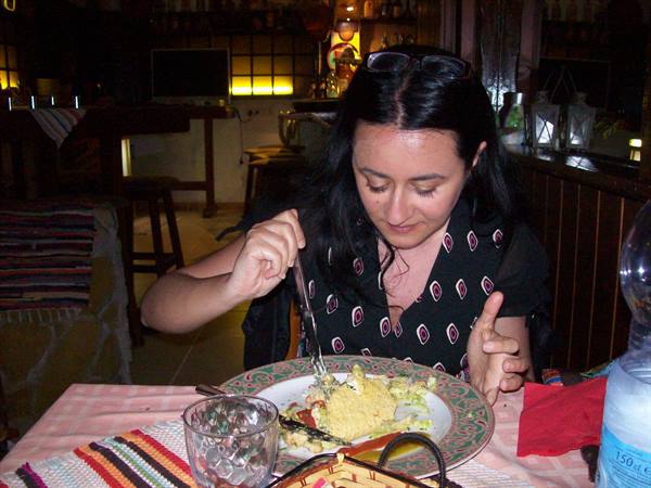 Woman eating salad and rice at restaurant, warm lighting and pink tablecloth