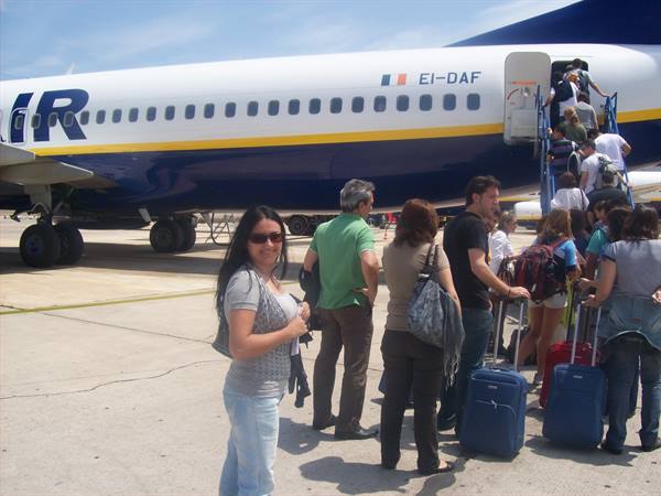 Passengers with suitcases boarding a Ryanair plane via mobile stairs