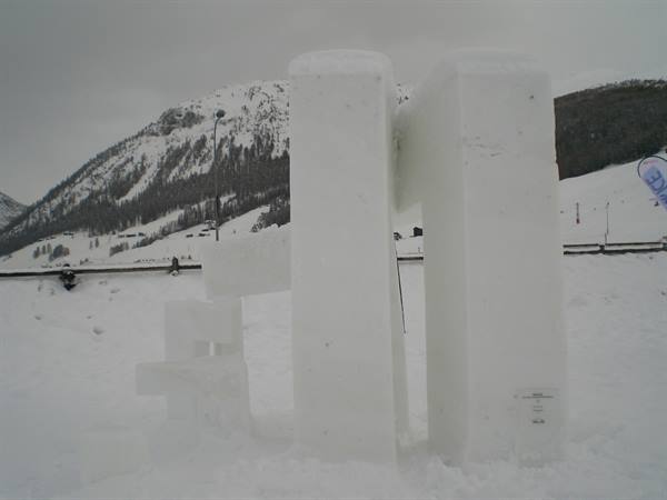 Snow sculptures shaped like numbers in a snowy field with mountains
