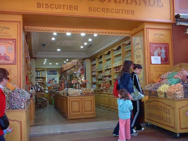 Yellow biscuit shop entrance with colorful candies and sweets, customers outside