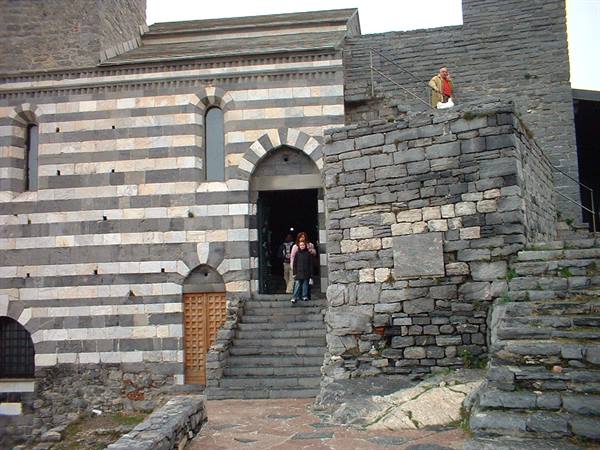 Tourists descend the stone steps of the black and white striped church of Portovenere