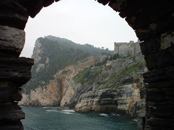 Portovenere, cliffs and castle seen through a dark stone arch