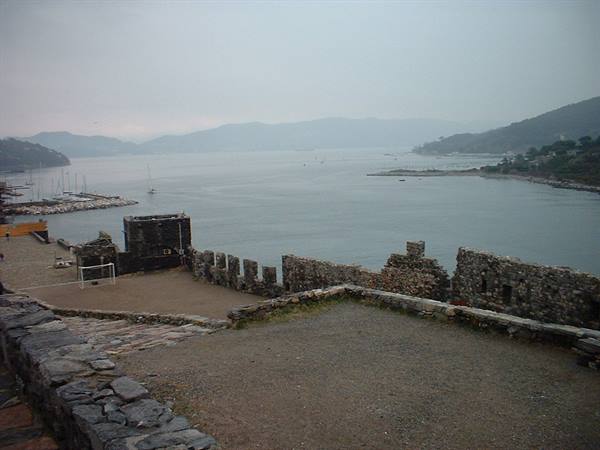 Old stone walls over Portoferraio harbour, grey sky and boats