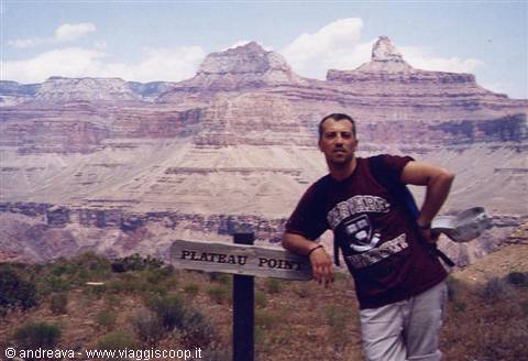 Man with backpack leaning on Plateau Point sign, Grand Canyon