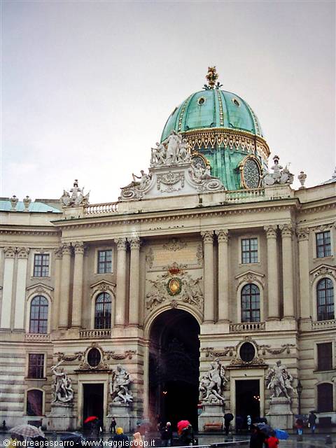 Hofburg in Vienna: green copper dome, baroque statues and people with umbrellas in the rain