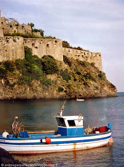 Blue and white fishing boat in front of the old Aragonese castle walls