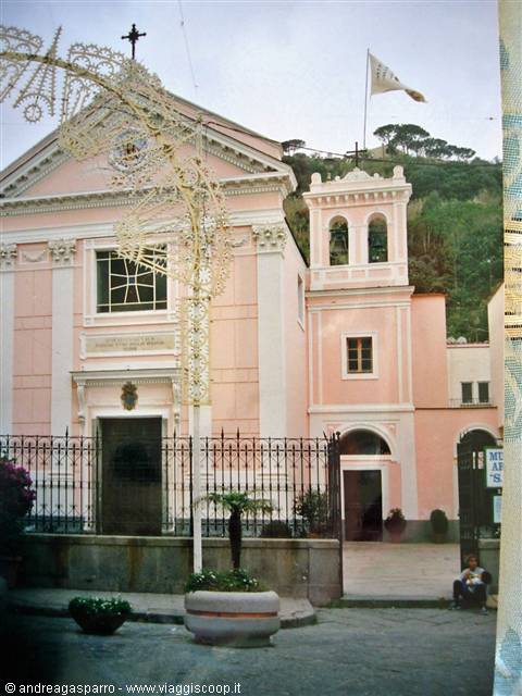 Pink church with bell tower, iron railings and festive lights out front