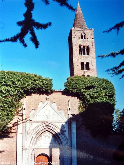 Brick bell tower with spire above an ivy-covered marble Gothic portal, blue sky