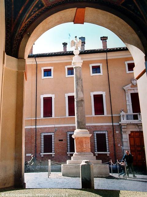 Column topped by marble eagle framed by arch, ochre palace behind