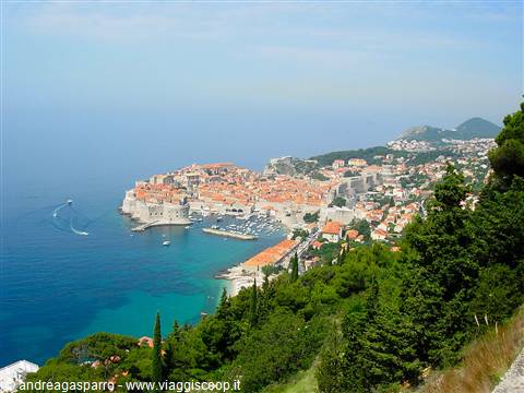 Dubrovnik old town with orange rooftops, harbor and boats seen from hill